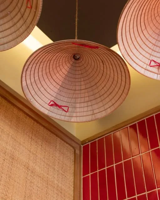 Conical hats hung as lampshades above terracotta tiles