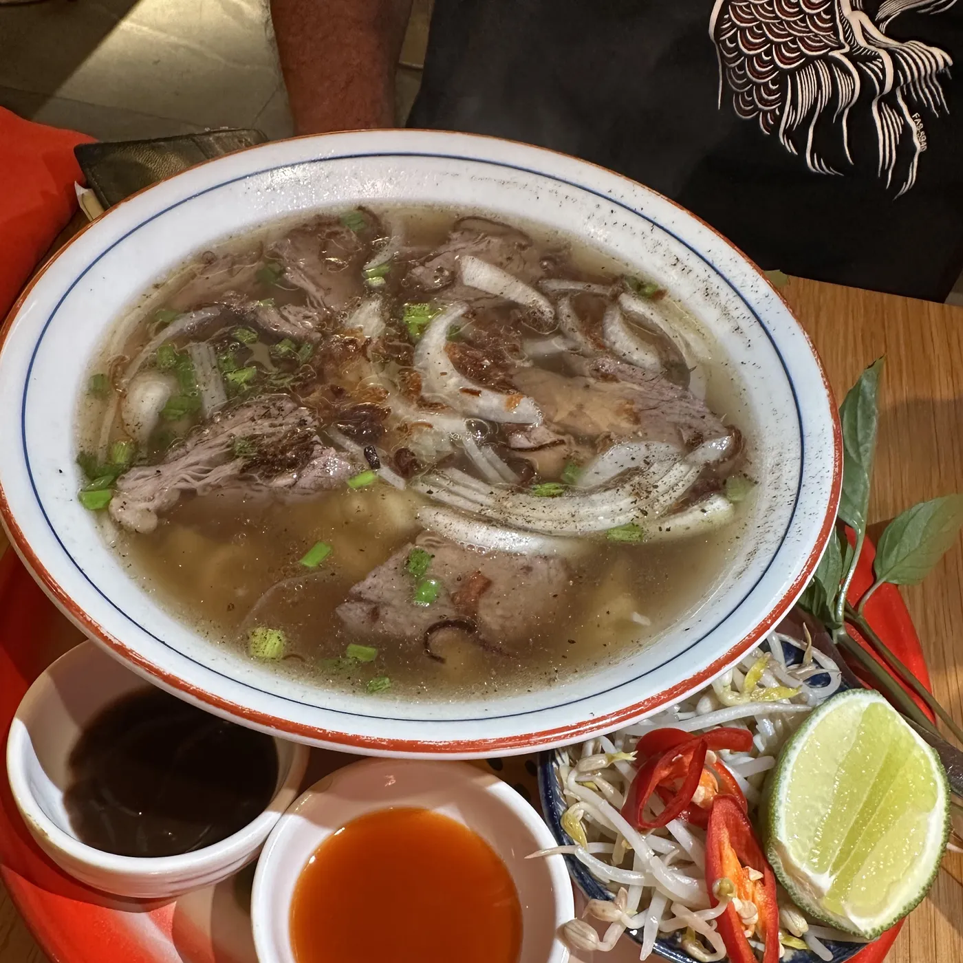 A bowl of phở bò with beef, herbs and lime